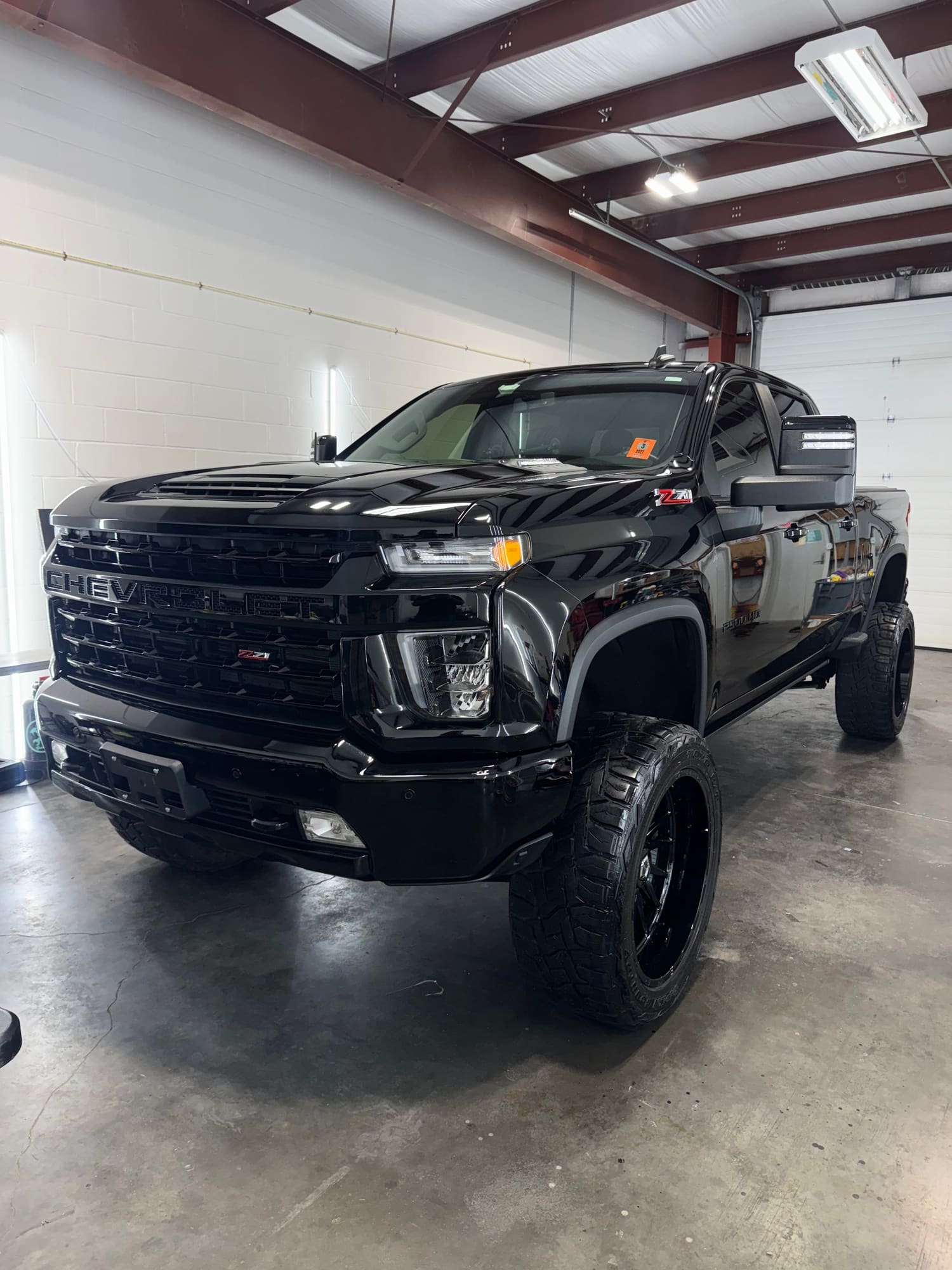 Black Chevrolet Silverado Z71 off-road pickup truck parked inside a garage with white walls and a metal ceiling.