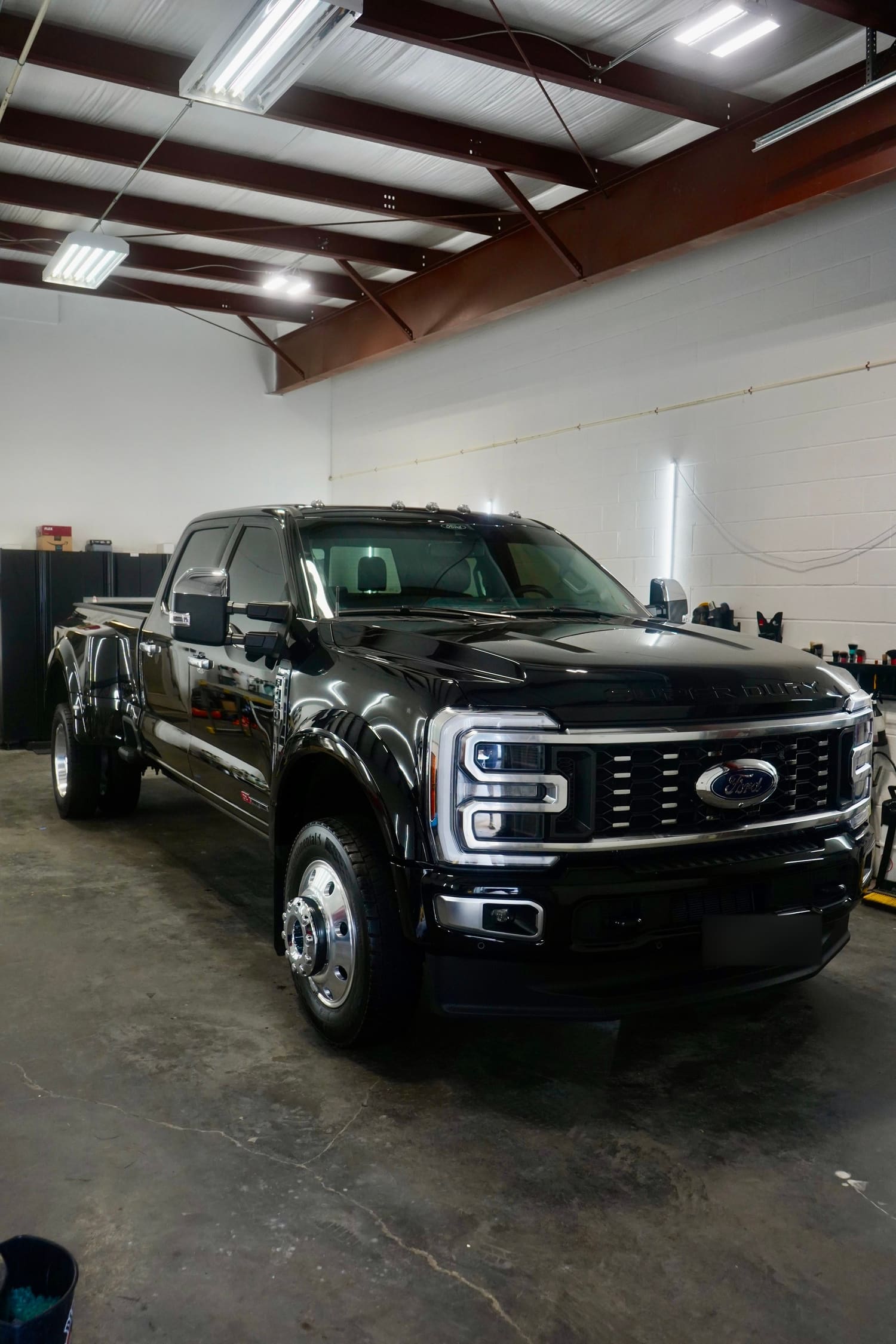 Black Ford Super Duty pickup truck parked indoors in a garage or workshop.