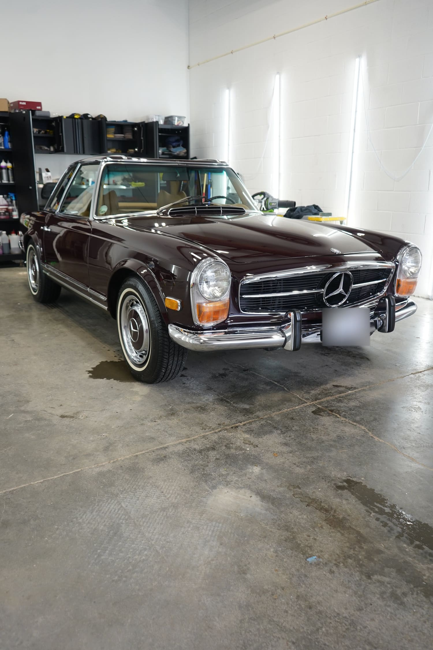 A vintage maroon Mercedes-Benz car parked inside a garage.