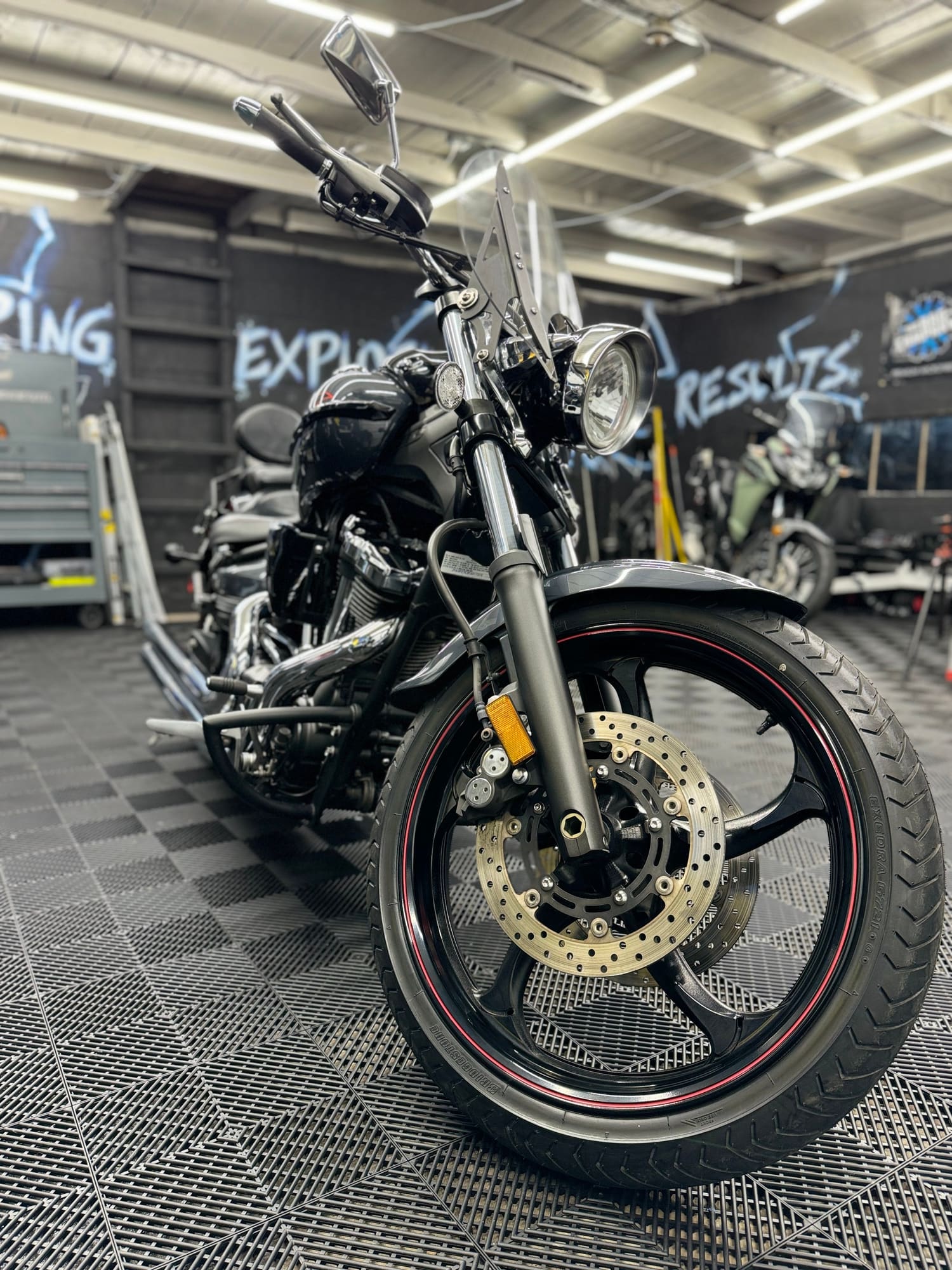 Black motorcycle with a windshield displayed indoors