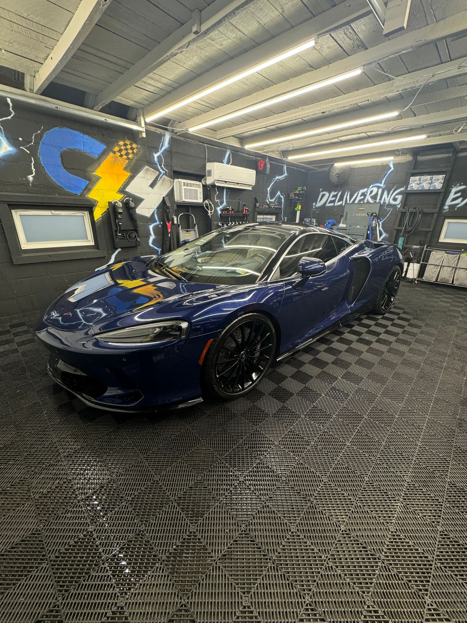 Blue sports car on the checkered floor inside the C4 Auto Detailing shop