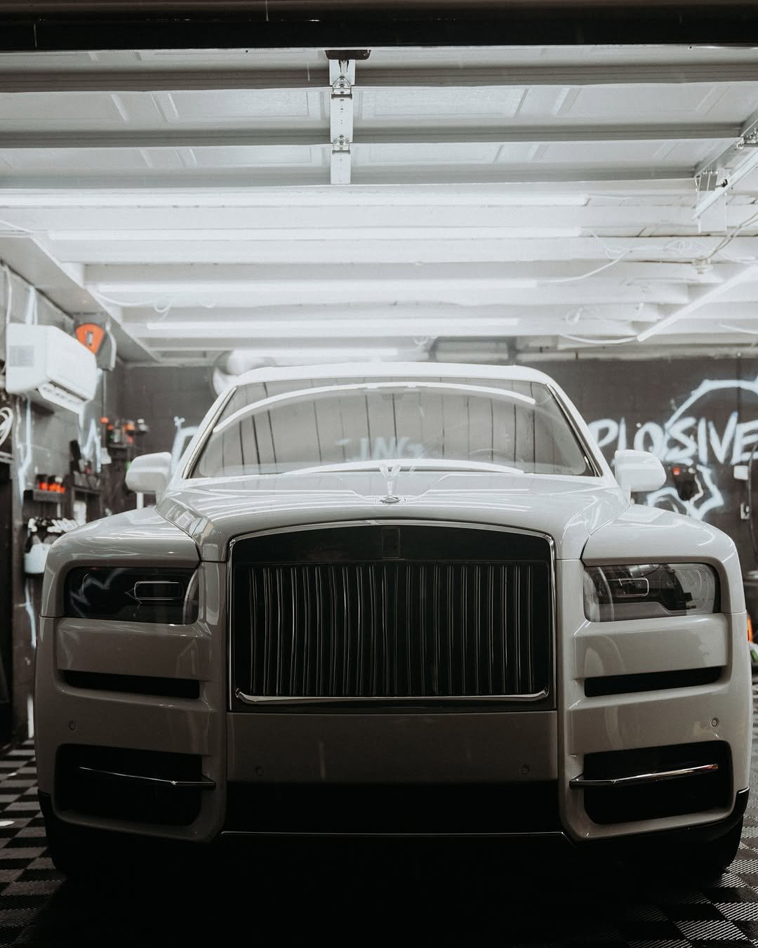 Front view of a white luxury car inside a garage.