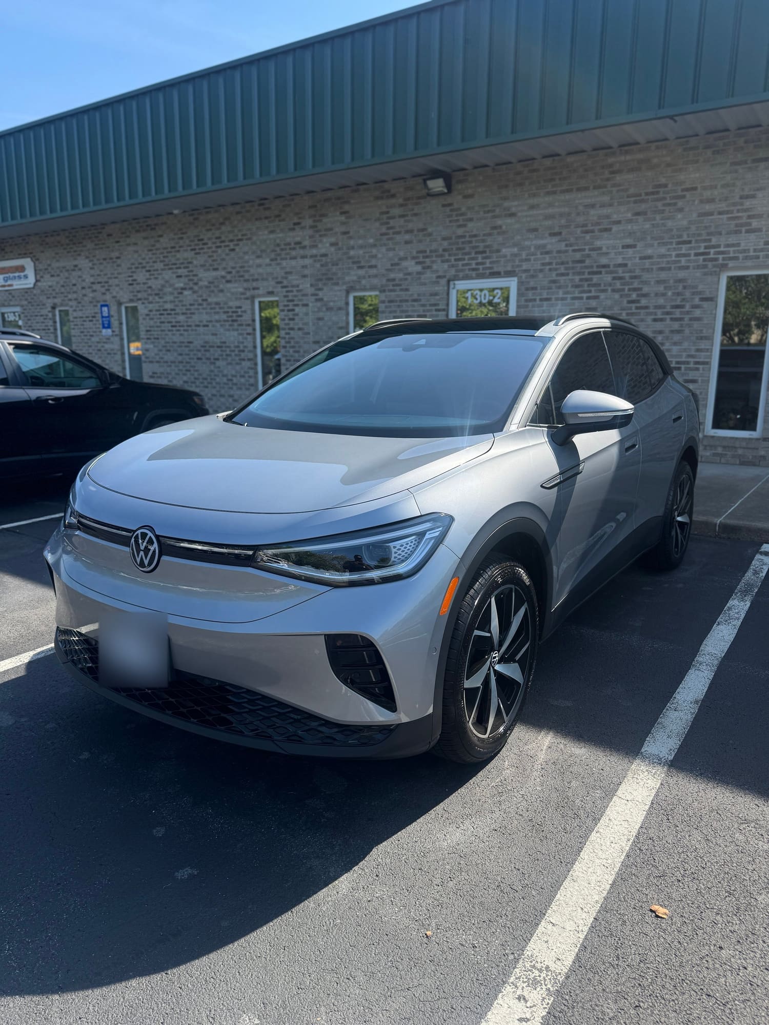 Silver Volkswagen electric vehicle parked in a parking lot during daytime.